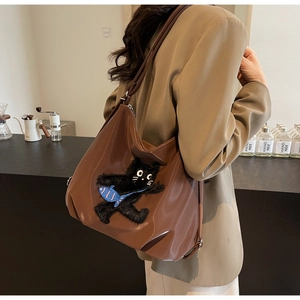 Détail d'un sac cabas marron avec broderie de chat noir et boucle en métal argenté