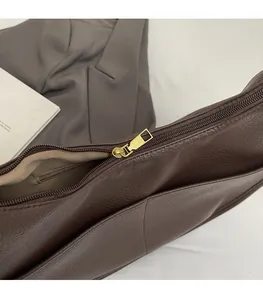 Detailed macro view of smooth metal zipper and brown leather texture on handbag