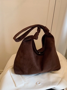 Retro dark brown suede tote bag with stylish knot strap on white blazer backdrop