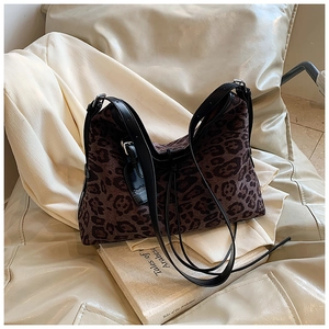 Detail of leopard print tote bag with black leather strap and golden metal buckle
