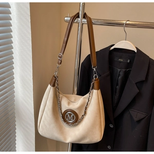 Detail of off-white suede tote with brown leather trim and metallic chain decoration