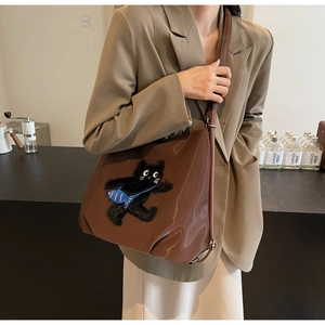 Sac fourre-tout en cuir marron avec écusson chat noir dans un décor de style de vie