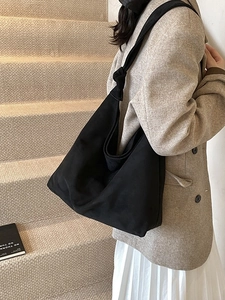 Vintage black matte tote bag with wide knotted strap worn by a model in a minimal setting