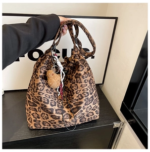 Close-up of leopard print bucket bag with drawstring and cute brown plush bear pendant
