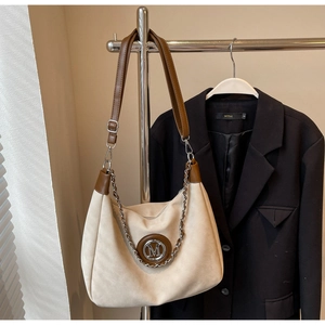 Detail of hobo bag with M logo, silver chain decoration and dark brown shoulder strap