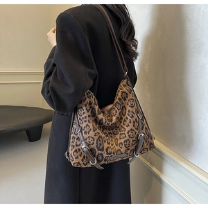 Dettaglio borsa leopardata con tracolla in pelle marrone e fibbie metalliche di design