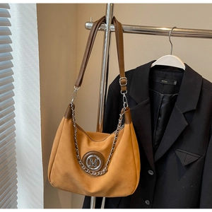 Detail of ginger hobo bag with silver chain and metal M logo on a clothing rack