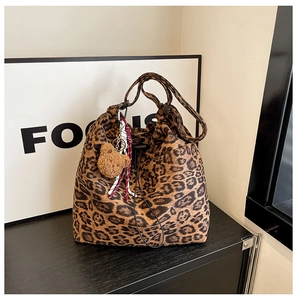 Detail view of leopard print shoulder bag with drawstring closure and plush bear charm