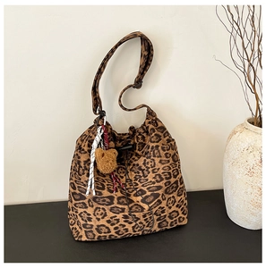 Detail of leopard print bucket bag with drawstring closure and brown plush bear charm