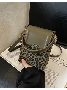 Olive green and leopard print crossbody mini bag with gold rivets on a fashion magazine