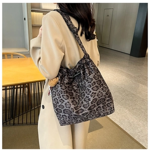 Close-up of leopard print bucket bag with drawstring and cute bear charm on beige coat