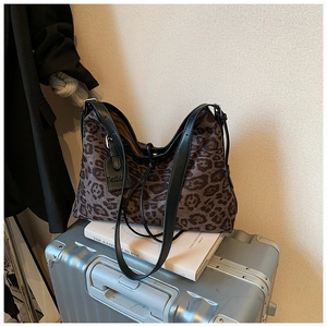 Close-up of leopard print tote bag with black leather straps and fashion tag detail