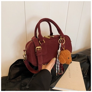 Dettaglio borsa Boston in camoscio bordeaux con hardware dorato e charm cane