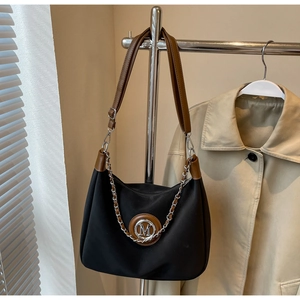 Detail of black nylon shoulder bag with brown leather trim and silver metal chain strap