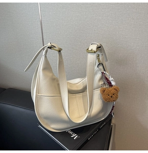 Detail of white litchi grain leather shoulder bag with bear pendant and adjustable strap