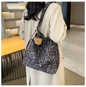 Detail of grey leopard print bucket bag with drawstring closure and plush bear charm