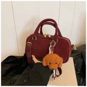 Dettaglio borsa Boston bordeaux opaca con doppi manici e ciondolo a forma di cane