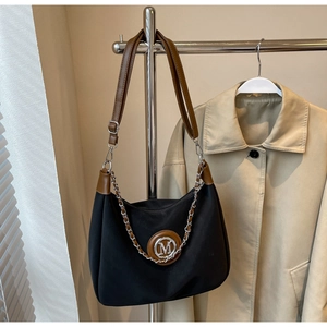 Detail of black nylon shoulder bag with brown leather handle and metallic silver chain