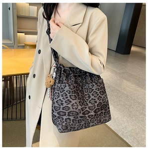Detail of leopard print bucket bag featuring drawstring closure and plush bear charm