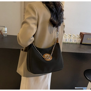 Detail of black nylon crescent bag with brown leather strap and silver chain on model