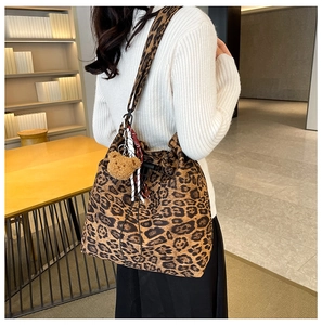Detail of leopard print bucket bag with plush bear charm and spacious fabric texture
