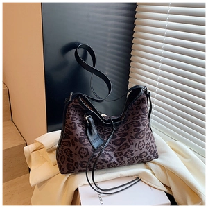 Detail of leopard print tote bag with black leather straps and fashion tag detail
