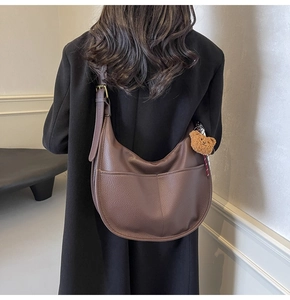 Close-up of deep brown pebbled leather hobo bag with a cute teddy bear charm detail