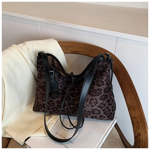 Detailed view of the leopard print fabric texture and leather strap on the tote bag