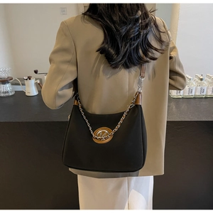 Detail of canvas crescent bag with leather trim and silver chain on beige blazer