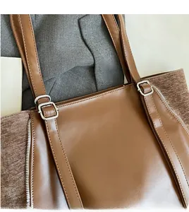Dettaglio degli spallacci regolabili con fibbie argentate su borsa shopping marrone