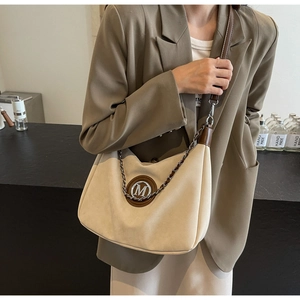 Detail of beige and brown crossbody bag with metal M logo and elegant chain strap