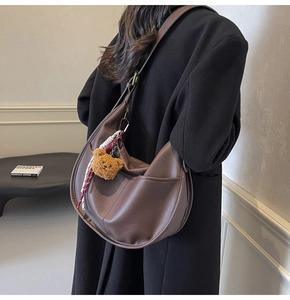 Deep brown pebble leather hobo bag with teddy charm shown on a black winter coat