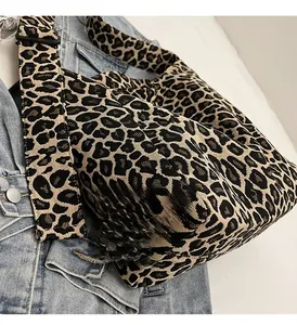 Détail du cabas en toile léopard avec bandoulière réglable sur fond de vêtement en jean