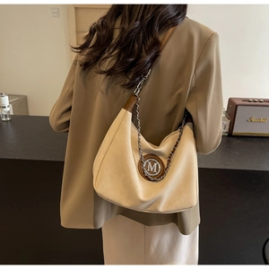 Detailed back view of a beige suede hobo bag with gold metal M logo and chain strap