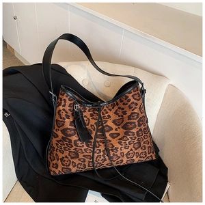 Detail of leopard print tote bag with black leather straps and fashion label on chair