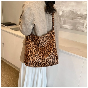 Detailed view of leopard print shoulder bag worn with a grey blazer and white skirt