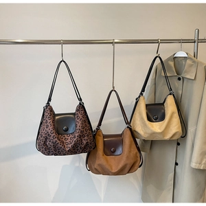 Detailed view of three suede tote bags in leopard, brown and beige colors with flaps