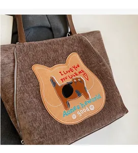 Dettaglio della borsa tote in velluto marrone con ricamo a gatto e cerniere decorative