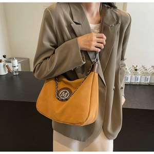 Close-up of yellow suede hobo bag with gold metal M logo and stylish chain detail