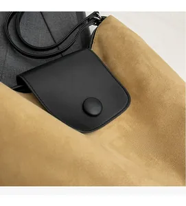Detail of premium beige suede tote bag with black leather flap and round buckle