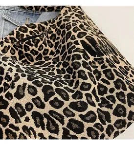 Gros plan sur la texture du cabas en toile léopard avec fond de veste en jean bleu