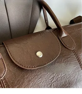 Close-up of brown pebbled leather handbag featuring silver hardware and fine stitching