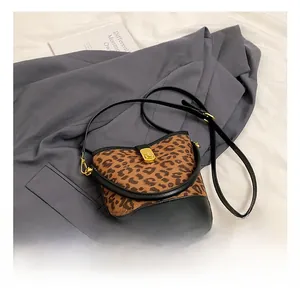 Detail showing leopard print fabric texture and shiny gold clasp on the vertical bucket bag
