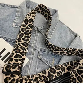 Détail d'un sac léopard avec une large bandoulière tissée réglable et boucle noire