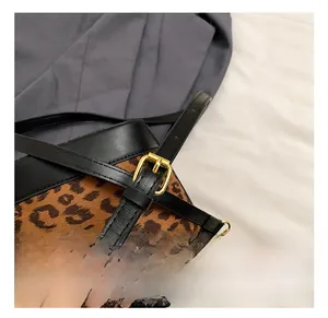 Detail of adjustable shoulder strap and gold metal buckle on leopard print handbag