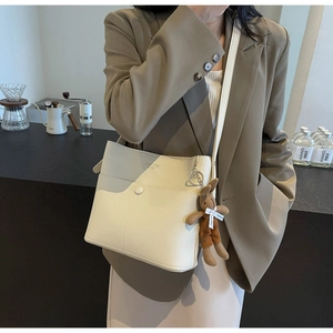 Chic cream bucket bag in lychee pattern leather with a cute plush bunny charm on model