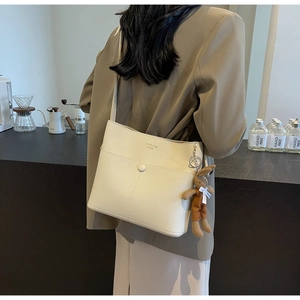 Detail of cream bucket bag with litchi texture and cute plush bunny charm
