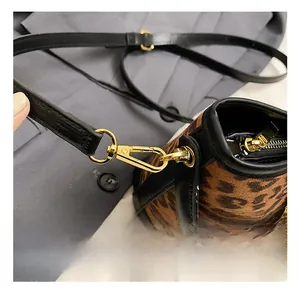 Detailed close-up of premium leopard print handbag with gold metal hooks and black strap