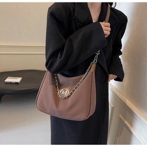 Detail of tan crescent dumpling bag with silver M logo hardware and chain strap