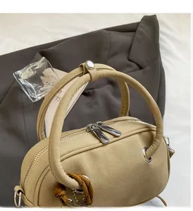 Détail d'un sac à main en cuir mat avec double fermeture éclair et poignée ronde
